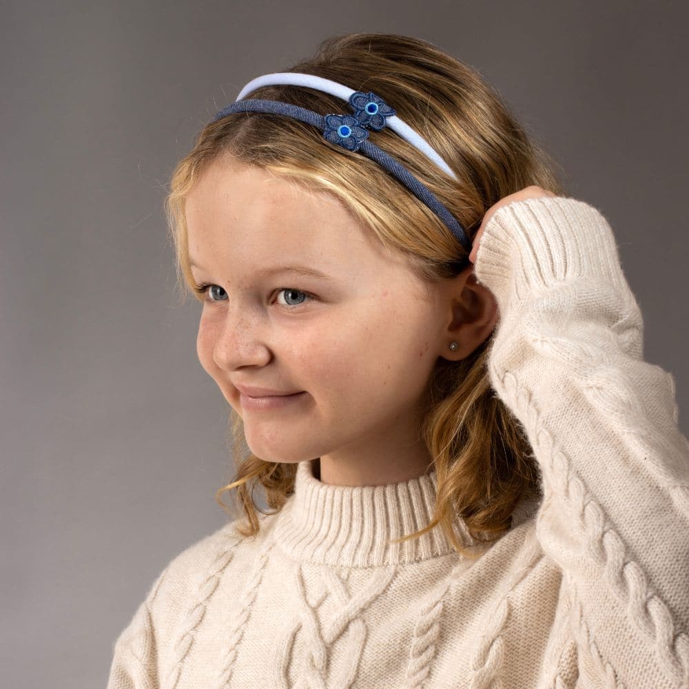 Girl tucking her hair behind her ears, wearing light and dark denim flower headbands at Tegen Accessories