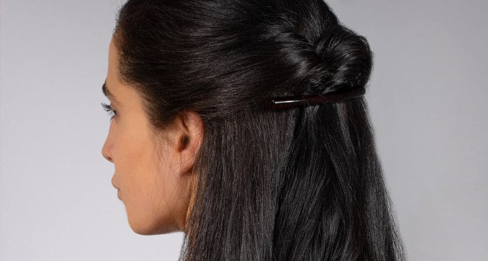 Dark hair swept back with a long narrow TEGEN barrette