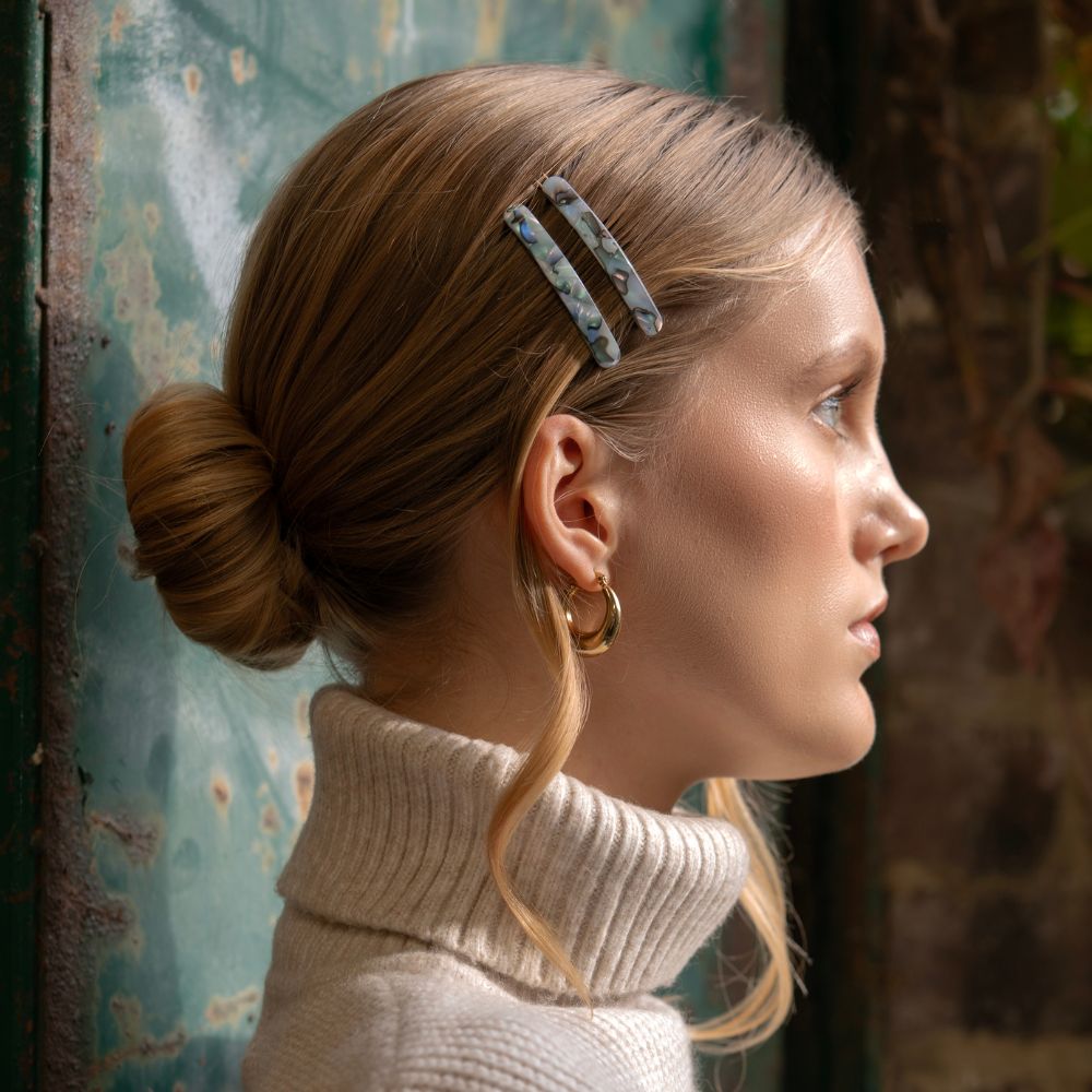 Woman with a bun and decorative hair clip against a textured wall